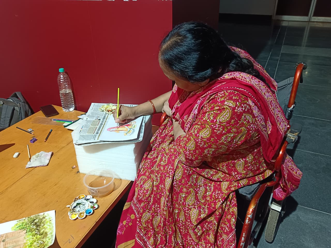 Woman sitting on wheelchair learning Patna Kalam painting